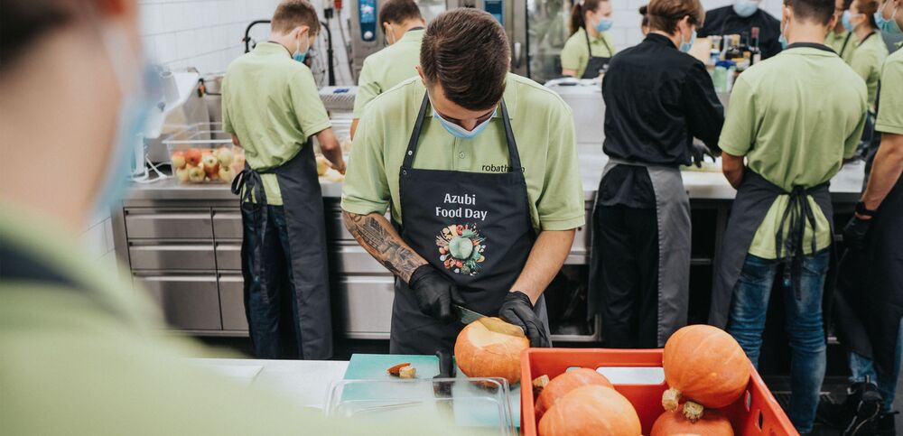 Highly focused with knife and apron: Trainees, hungry to learn, prepare the day‘s main course.